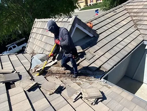 Worker lifting concrete roof tiles around a roof valley.